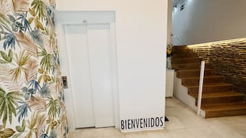 Un escalier avec une rampe en bois et une pancarte « BIENVENIDOS » au bas.