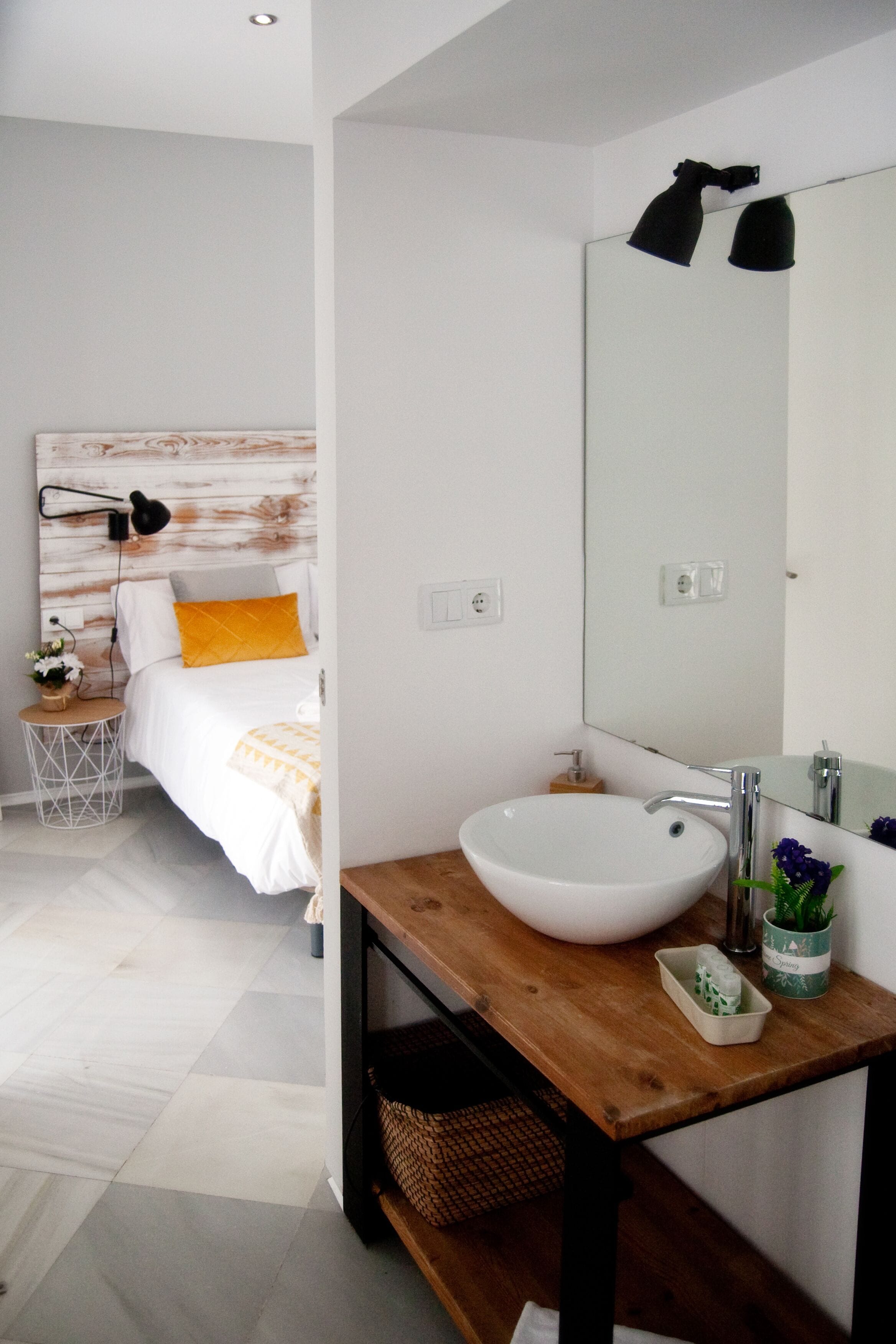 Un baño moderno con un lavabo blanco, tocador de madera y un espejo grande.