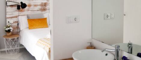 Un baño moderno con un lavabo blanco, tocador de madera y un espejo grande.