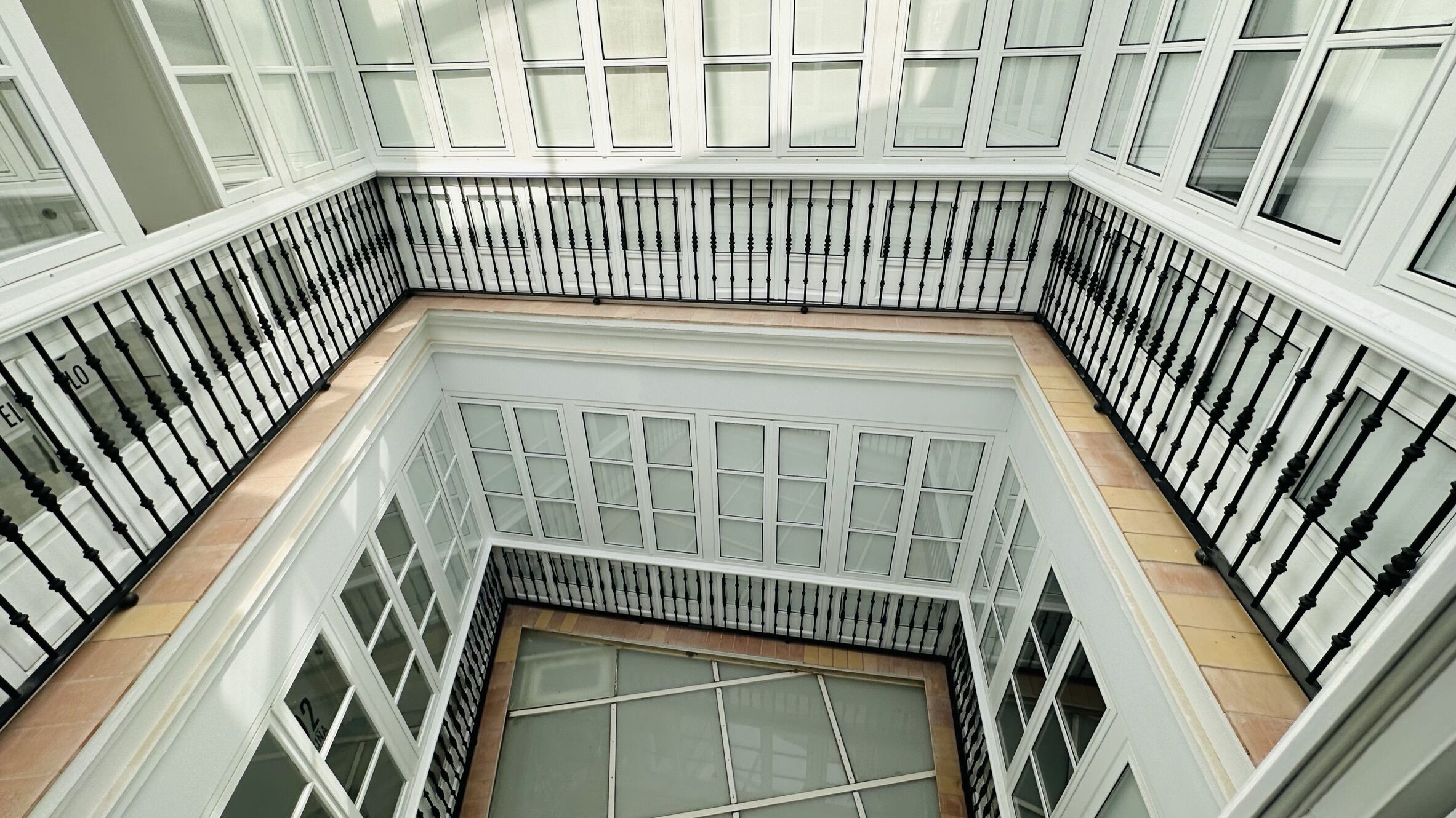 A high-ceilinged, open-plan interior with a central staircase and multiple windows.