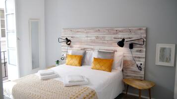 A neatly made bed with white and yellow linens, a wooden headboard, and bedside lamps.