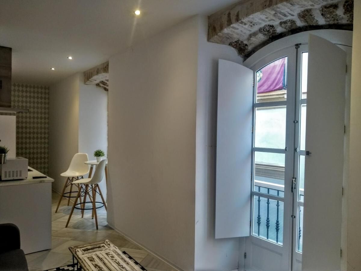 A hallway with a dining area, a white door with a window, and a patterned rug.