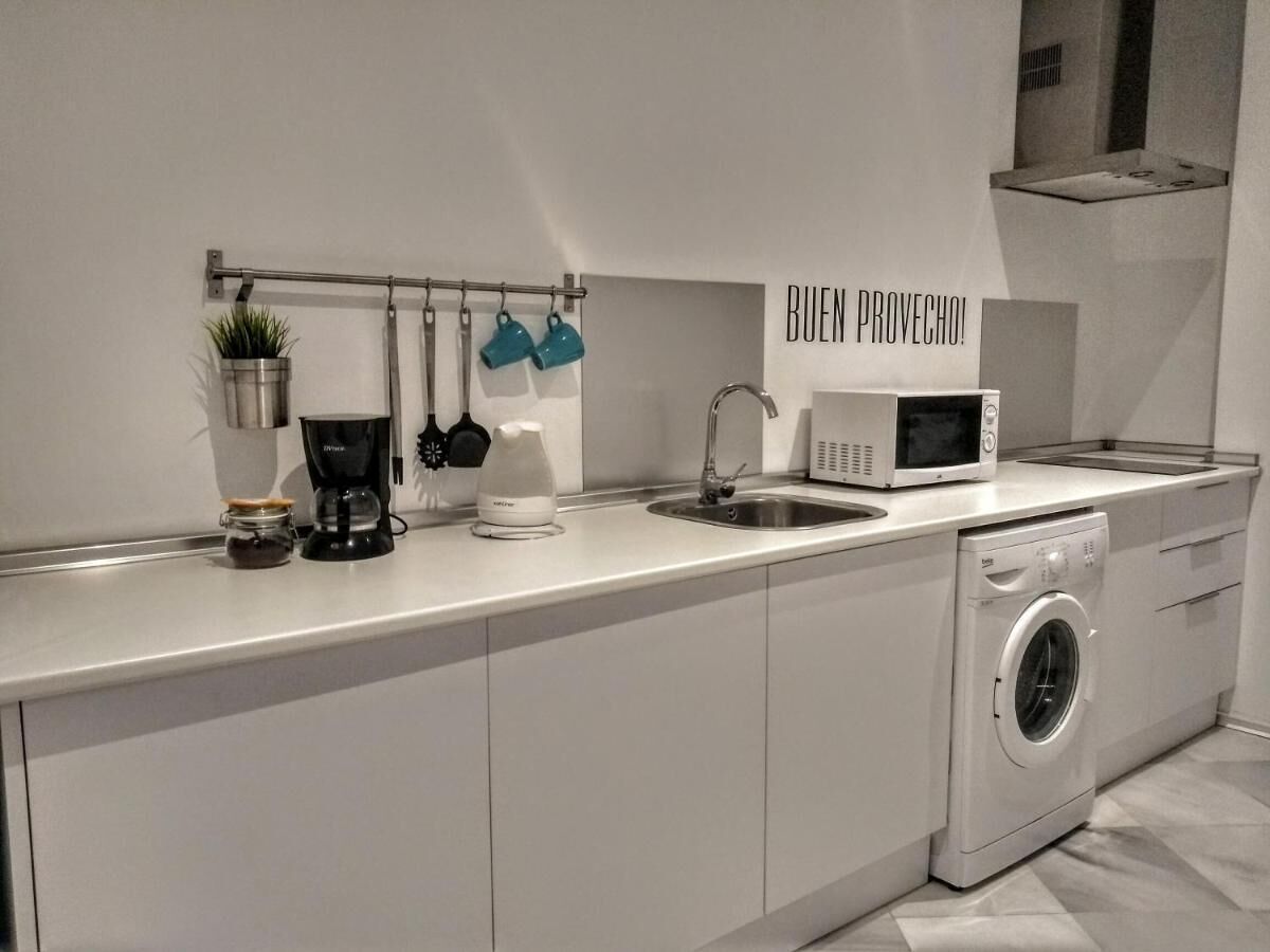 Et moderne køkken med vaskemaskine, kaffemaskine og mikroovn.