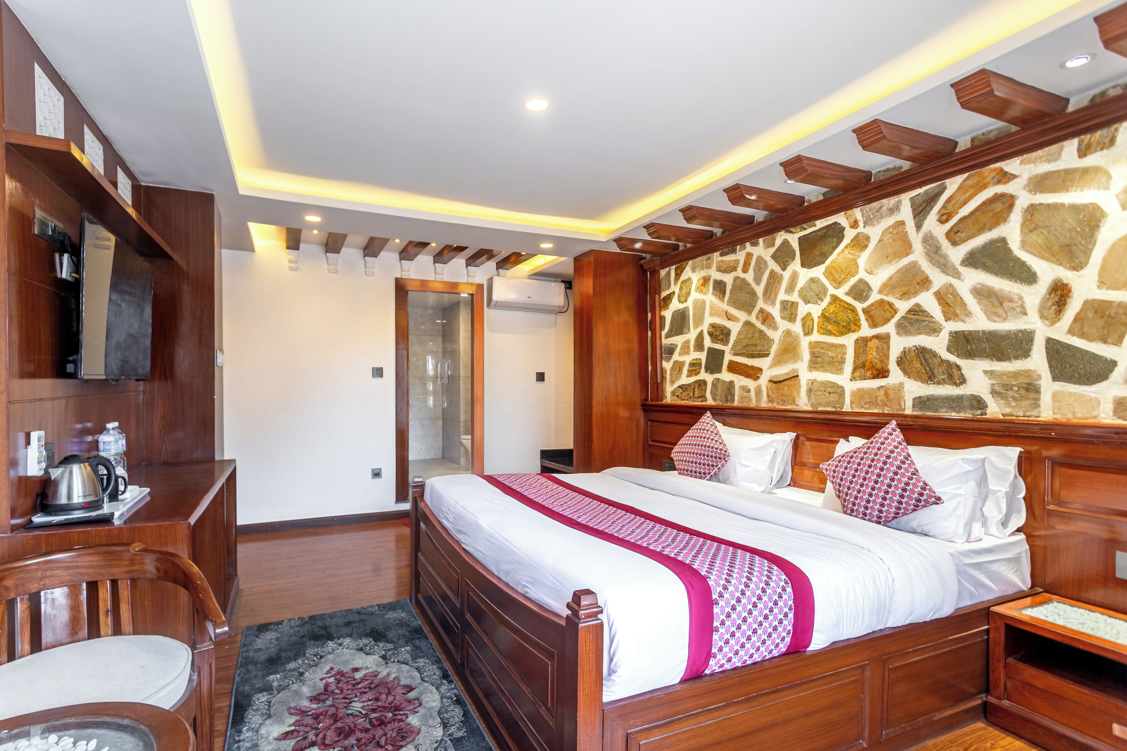 Een slaapkamer met een houten bed, een stenen muur en een bureau met een stoel.