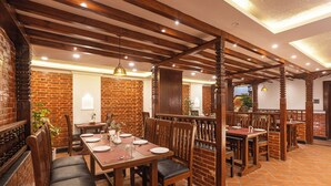 Un restaurante con paredes de ladrillo, vigas de madera y piso de baldosas. Mesas y sillas dispuestas para comer.