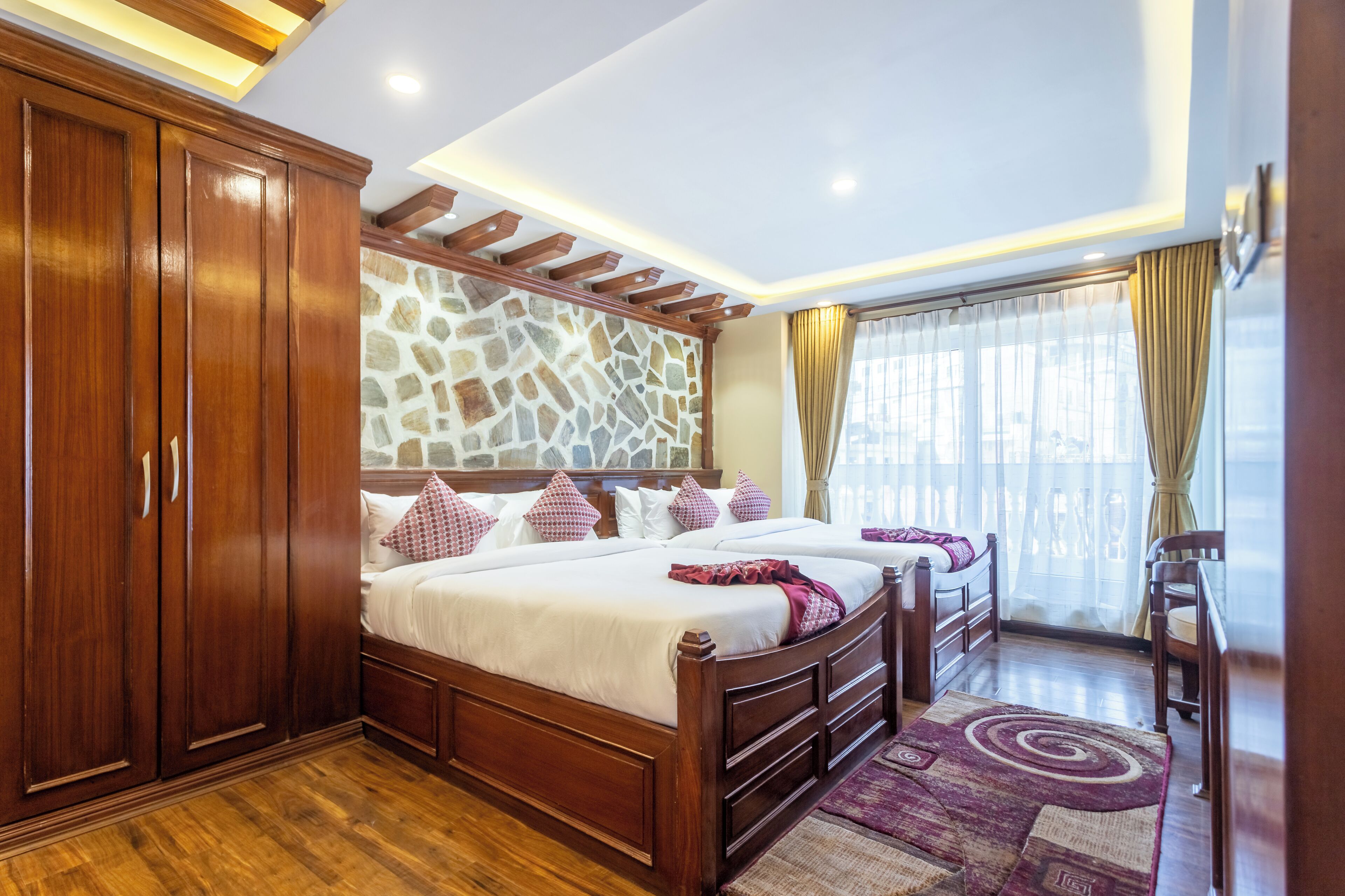 Una camera da letto con un letto grande, un armadio in legno, un muro in pietra e vista all'esterno da una finestra.