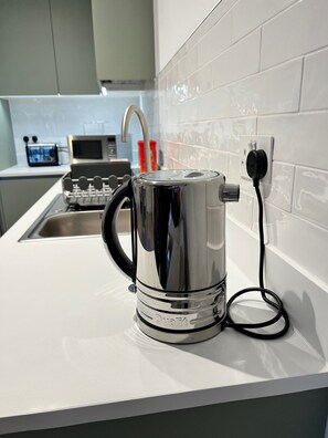 Kitchen equipped with a stainless steel kettle, microwave, and toaster.
