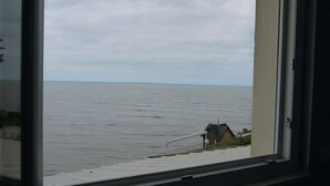 Vista d'una massa d'aigua des d'una finestra amb vistes a una escala que condueix a un edifici amb teulada inclinada.