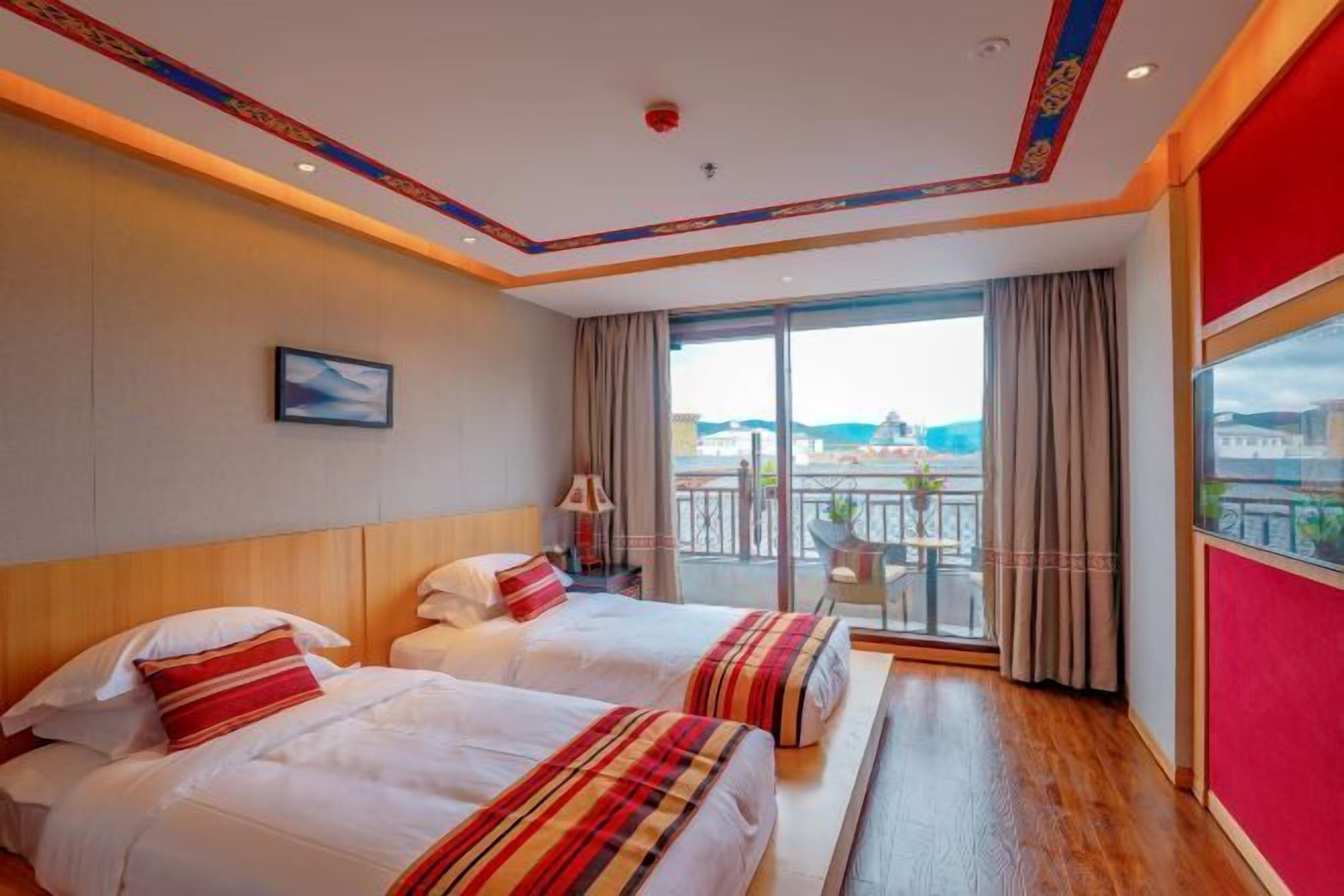 A hotel room with two beds, a large window with a view, and a balcony.