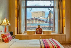 Ein Hotelzimmer mit einem Bett, einem Fenster mit Blick auf traditionelle Gebäude, einer Lampe und einem dekorativen Gegenstand an der Fensterbank.