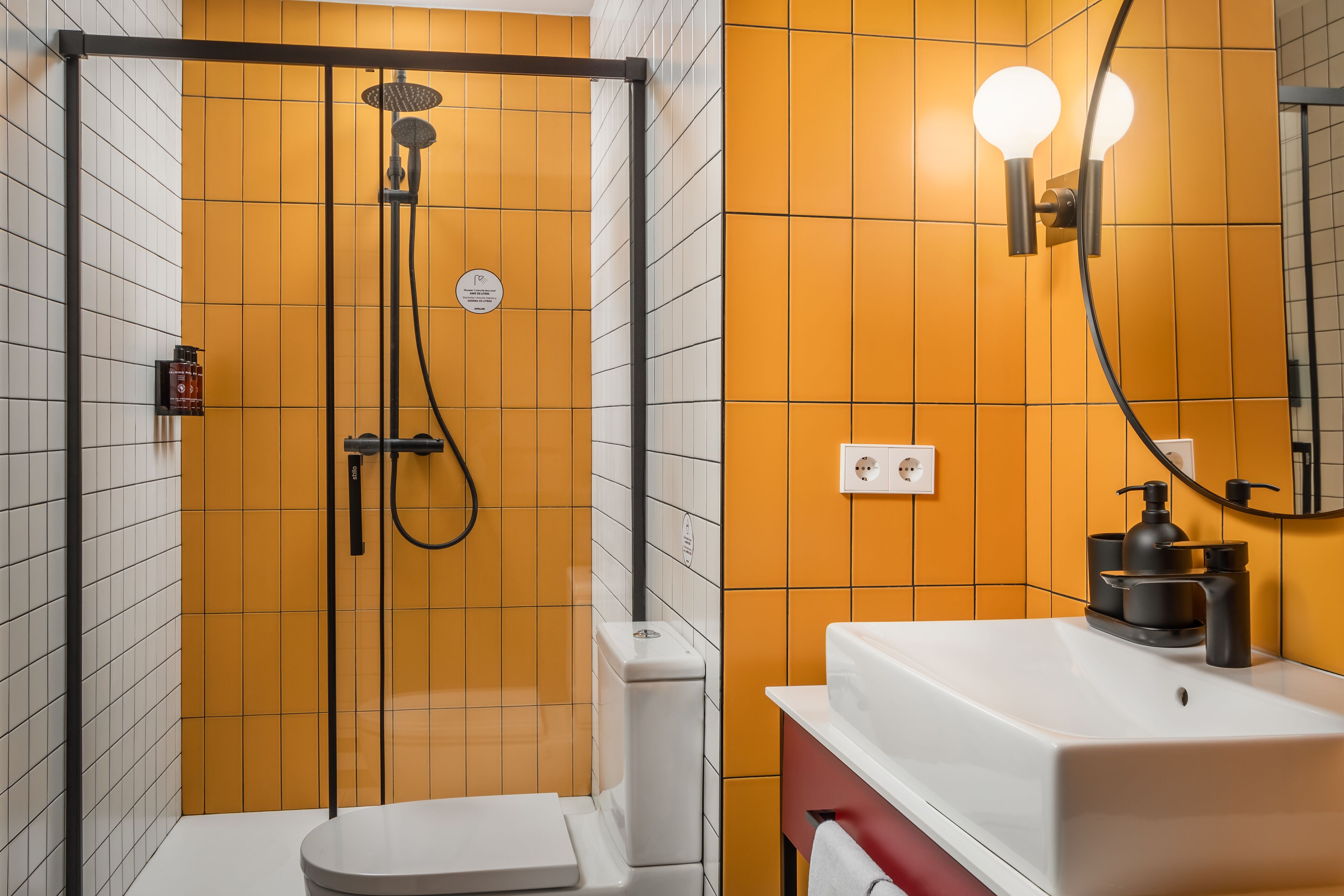 A bathroom with a glass-enclosed shower, a white toilet, and a sink with a mirror.