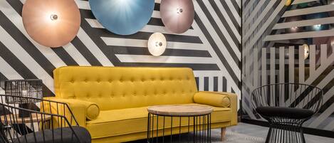 A modern interior with a yellow sofa, black chairs, and a patterned floor.