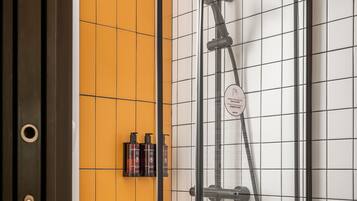 A modern shower enclosure with a glass door, a yellow tiled wall, and a black frame.