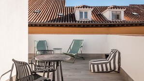 Una terraza con una mesa redonda y sillas, un sofá a rayas y un ventanal pequeño.