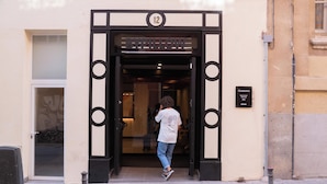 Entrada de hotel con una puerta numerada, un letrero que indica la ubicación y un ventanal.