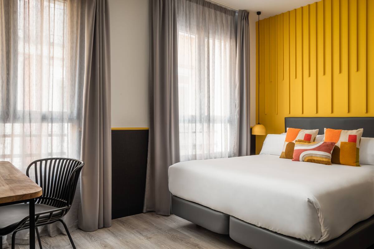 Quarto de hotel com cama, mesa e cadeira.