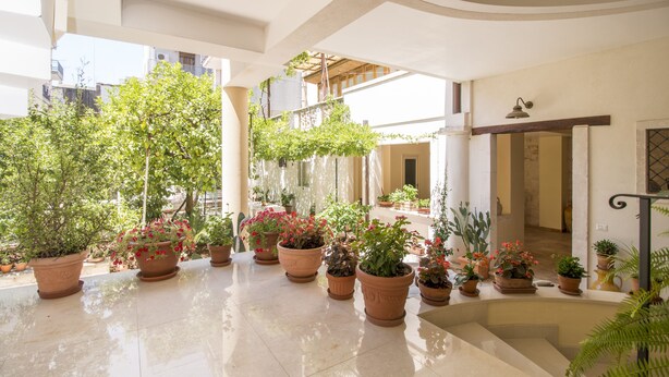 A spacious indoor courtyard with multiple potted plants and a tiled floor. - Court of Nobles (Conversano)