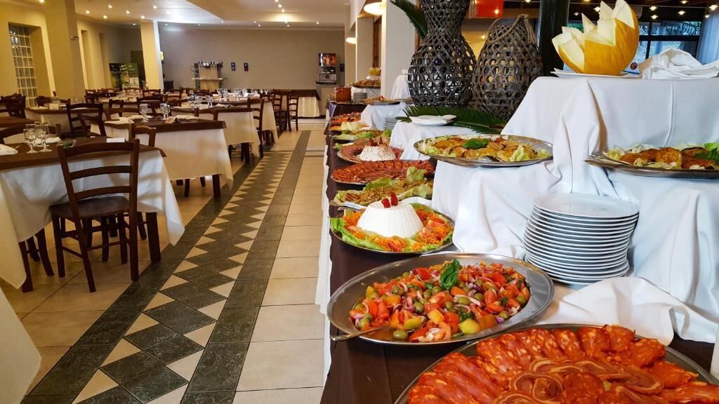 A buffet setup with various dishes, tables, and chairs arranged in a dining area.