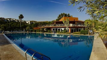 Relax by the pool surrounded by lush greenery and a scenic view.