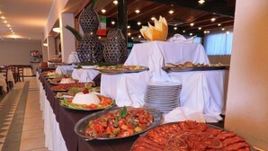 En buffet med forskellige retter, herunder et stort fad med pålæg samt et udvalg af salater og grøntsager.