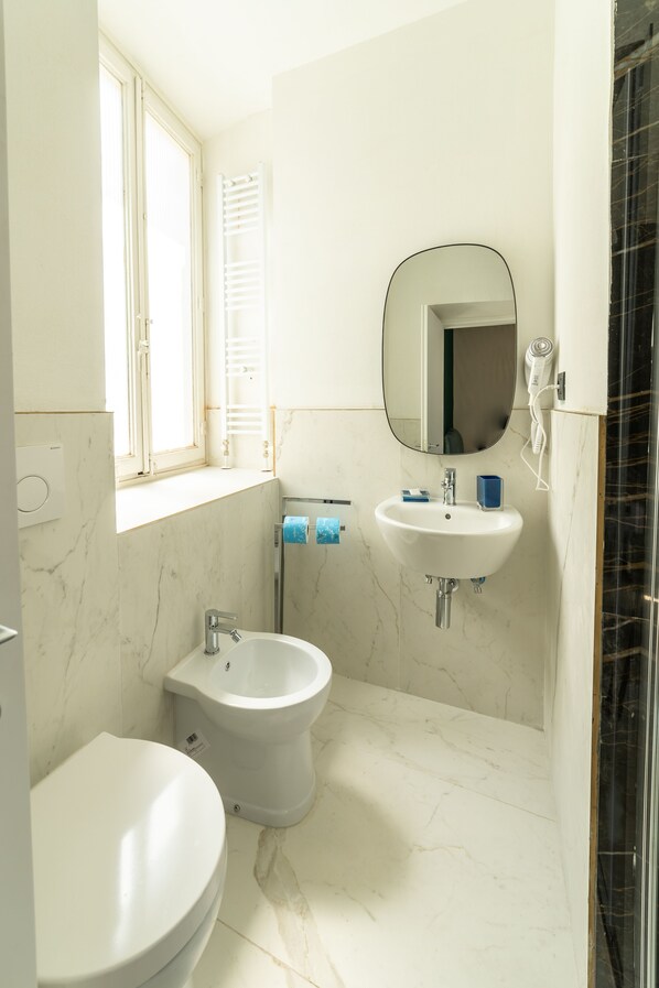 A bathroom with a toilet, bidet, sink, and mirror. - Room Eleven (Florence)