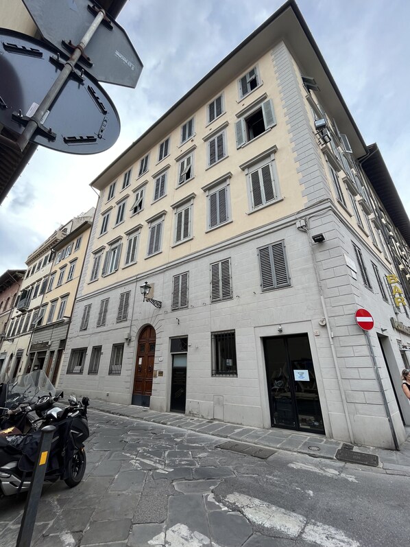 A multi-story building with a classic architectural style, featuring a central entrance with a wooden door and multiple windows with shutters. - Room Eleven (Florence)