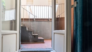 Une vue d’un escalier menant à un balcon doté de rampes en métal et d’un mur en béton.