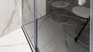 Une salle de bain moderne avec une douche à parois de verre, des carreaux de marbre, un lavabo et un porte-serviettes.