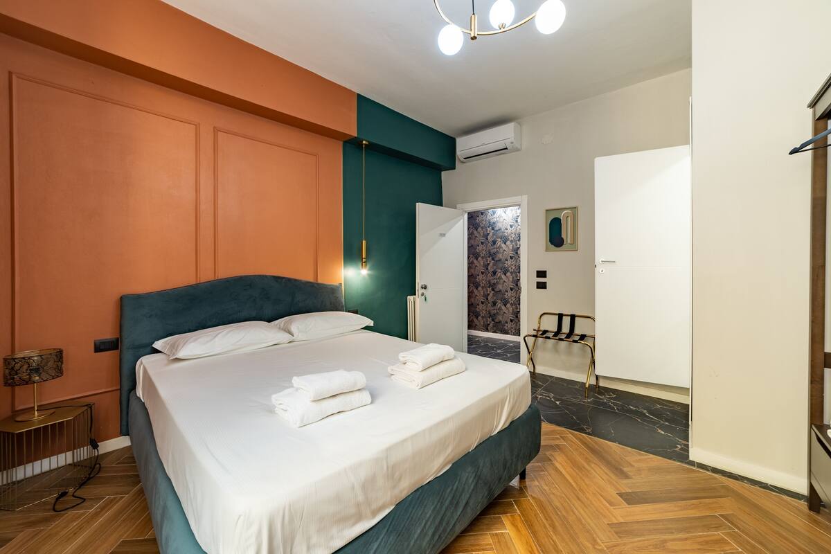 A modern bedroom with a large bed, a bedside table, and a hanging light fixture.