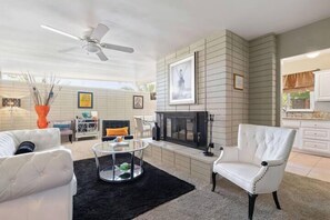 Cozy living area with a fireplace, comfortable seating, and a kitchen nearby.