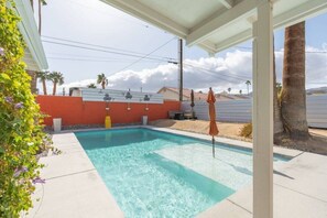 Relax by the rectangular pool surrounded by a shaded patio area and lush palm trees.