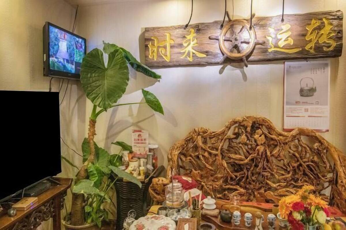 A room with a wooden sign, a television, a large plant, and a decorative wooden structure.