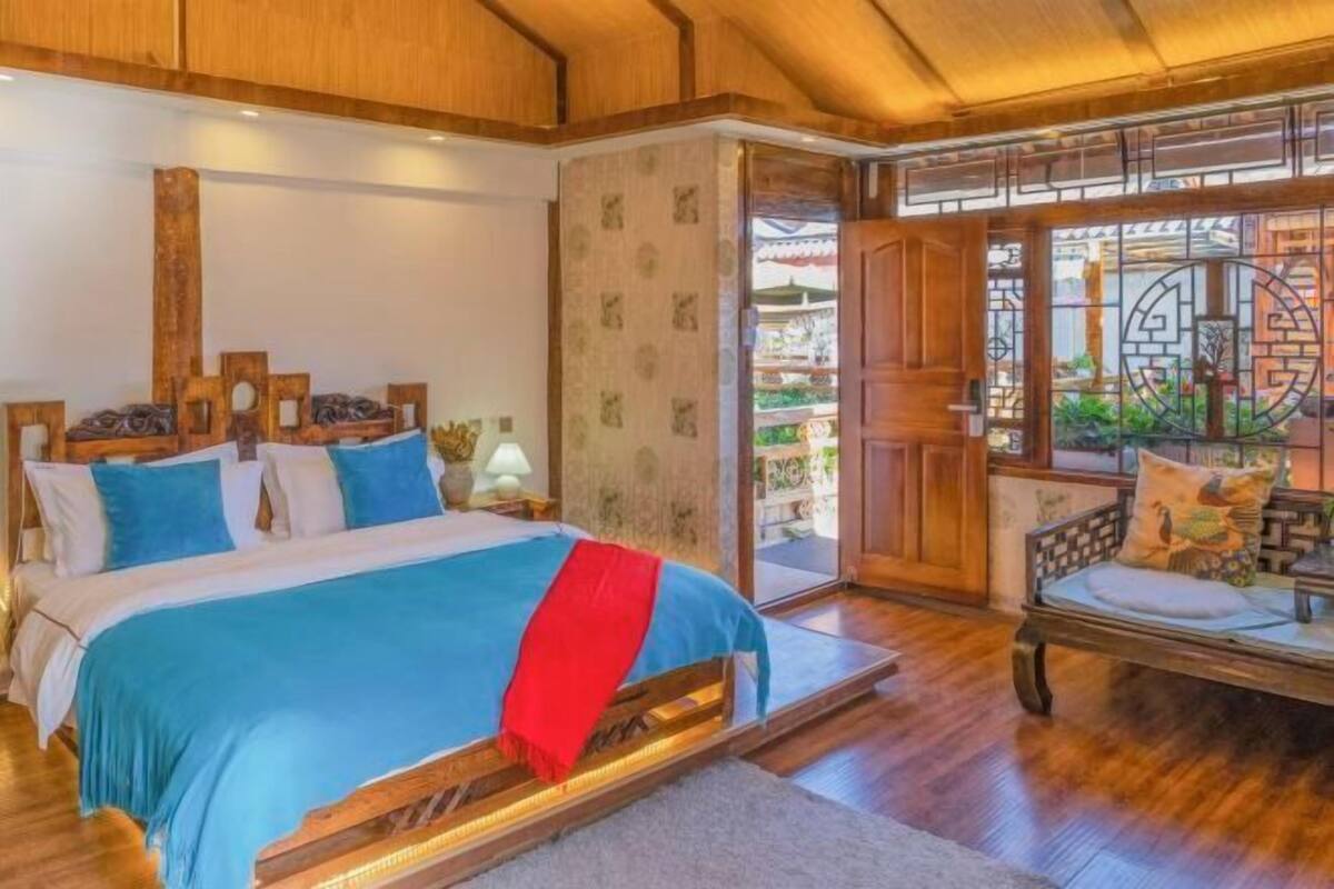 A traditional wooden room with a bed, a wooden chair, and a view through a patterned door.