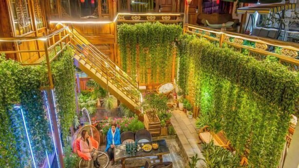 A multi-level atrium with wooden railings, a central staircase, and lush vertical gardens.