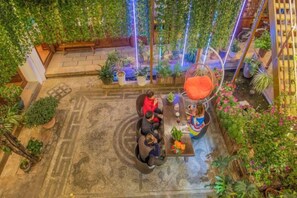 An indoor garden setting with a seating area, potted plants, and a water feature.