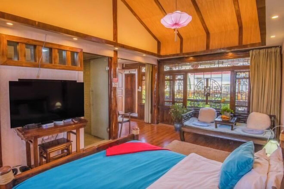 Ein Schlafzimmer mit Bett, Fernseher, Holzmöbeln und einem Fenster mit Blick.