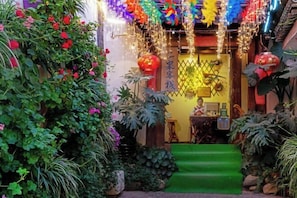 Ein traditioneller chinesischer Garten mit üppiger Vegetation, einem begrünten Eingangsbereich und dekorativen Laternen.