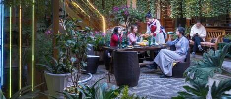 Un espace intérieur aménagé en jardin, avec un coin repas, des plantes en pot et un escalier.