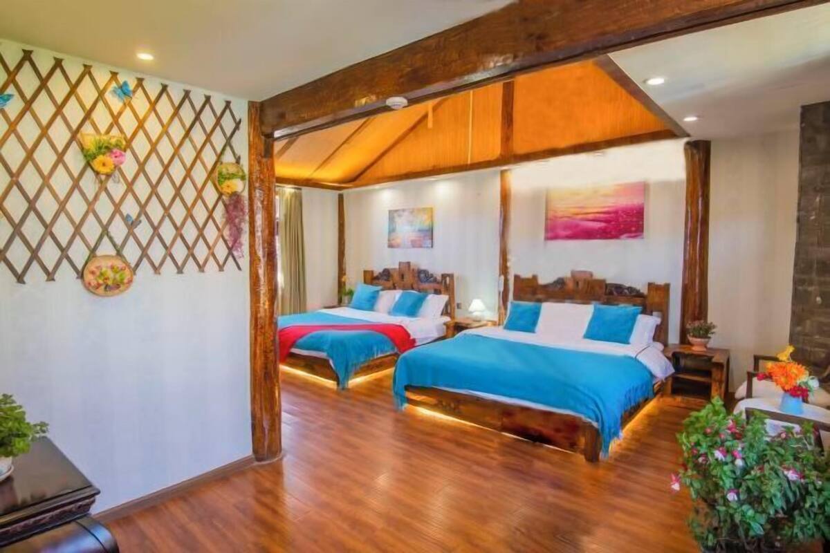 A room with two beds, wooden flooring, a lattice wall, and a painting.