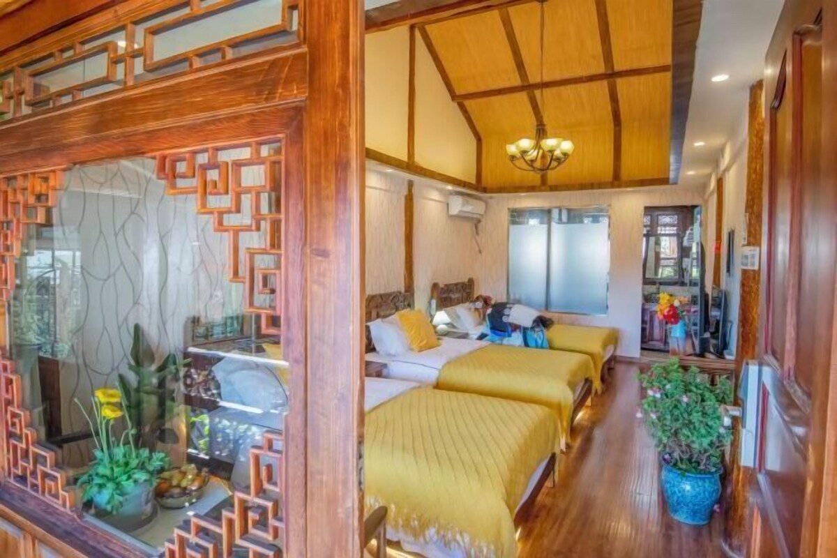 Ein Hotelzimmer mit Holzboden, zwei Betten mit gelber Bettwäsche, einem Kronleuchter und einem großen Fenster.