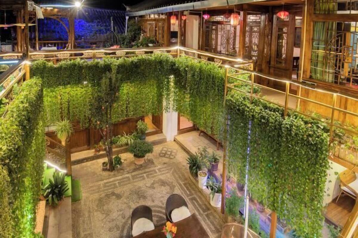 A rooftop garden with a seating area, potted plants, and traditional wooden architecture.