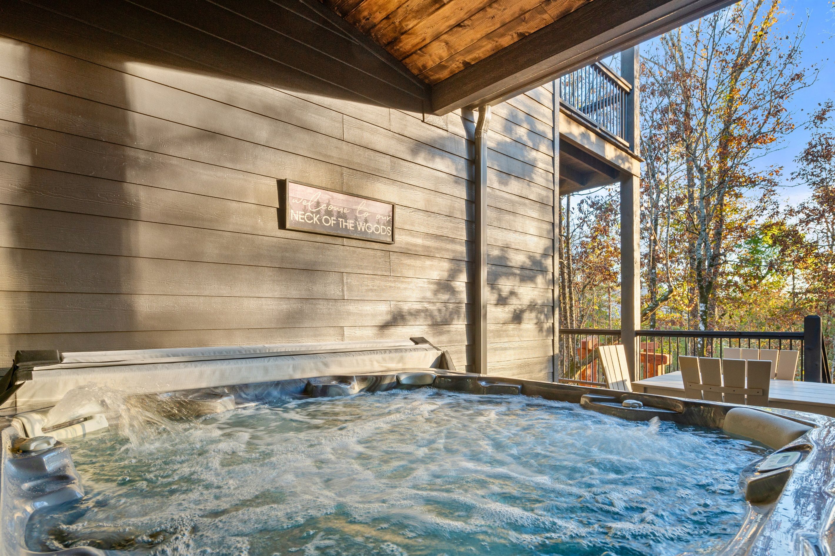 Un bain à remous avec une terrasse en bois et une pancarte sur laquelle on peut lire : « Bienvenue chez nous, au cœur de la nature. »
