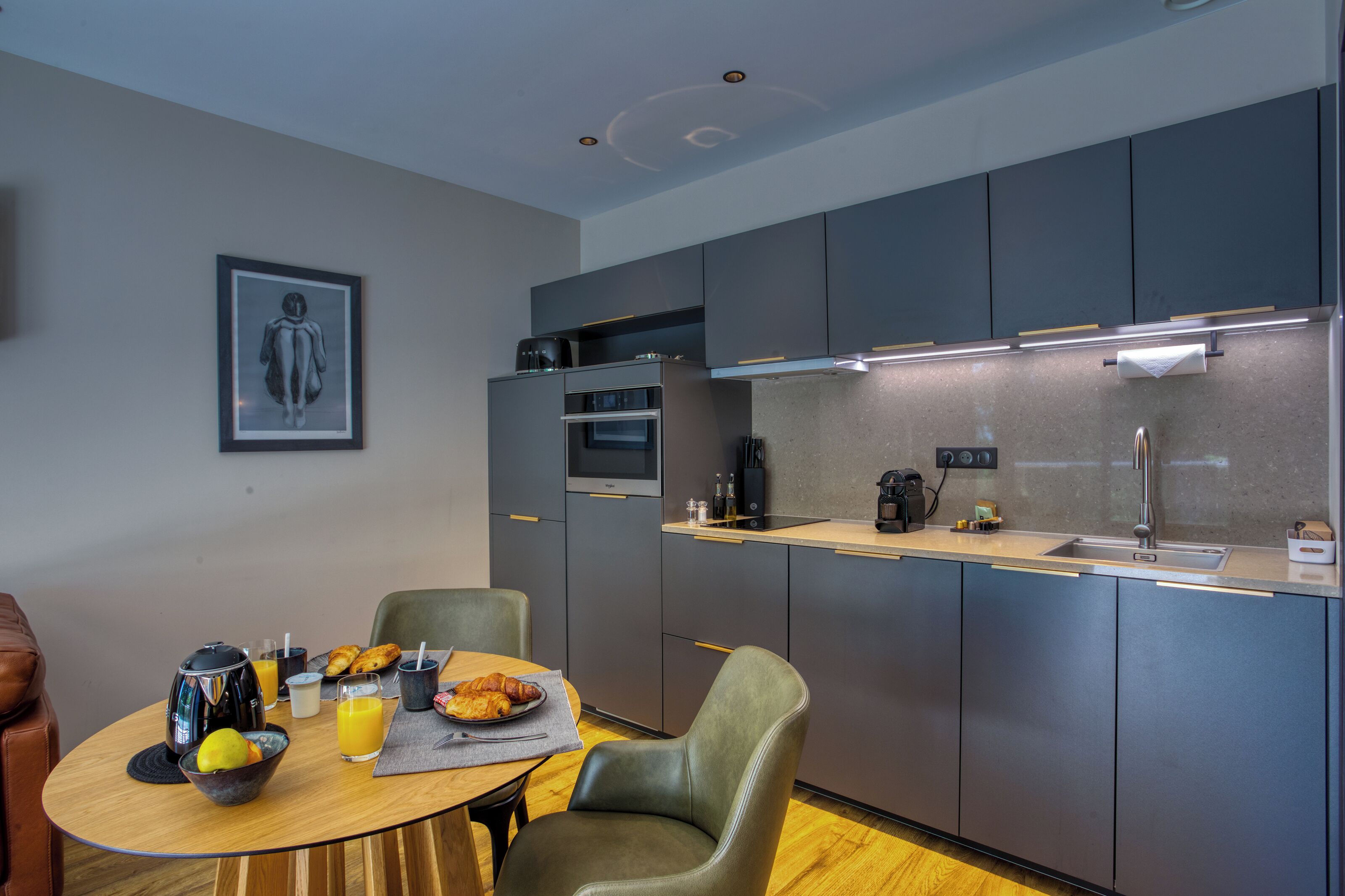 A modern kitchen with grey cabinets, a built-in oven, and a countertop with a coffee maker.