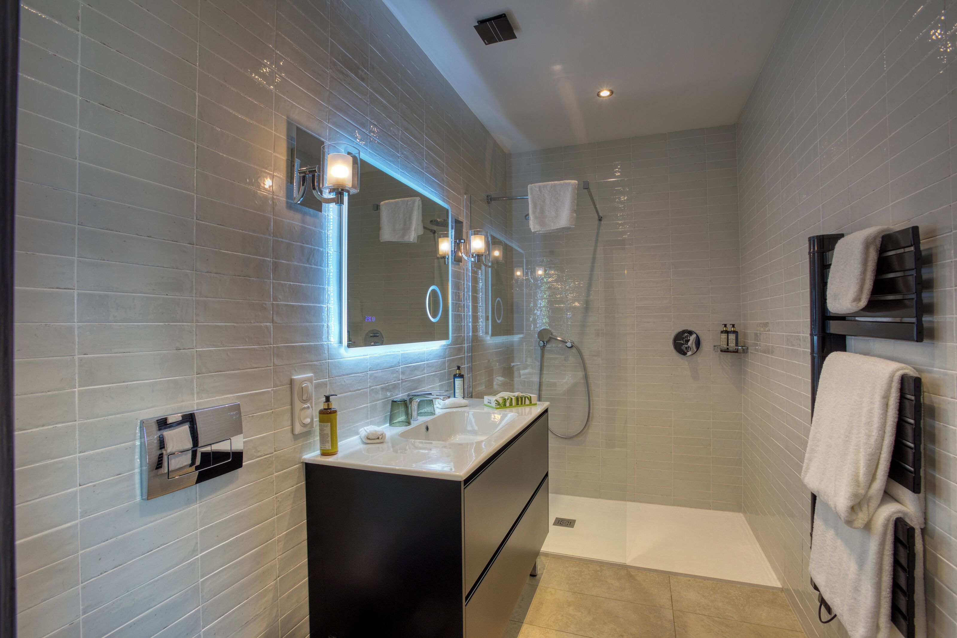 Un baño moderno con un espejo grande, un lavabo y una zona de ducha.
