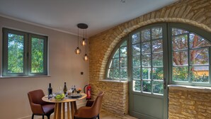 Un comedor con pared de piedra, un amplio ventanal arqueado y una mesa dispuesta para cuatro comensales.
