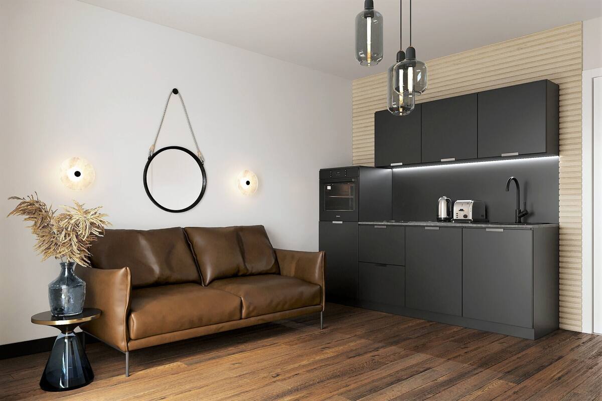 A modern kitchen with dark cabinetry, a built-in oven, and a coffee maker.