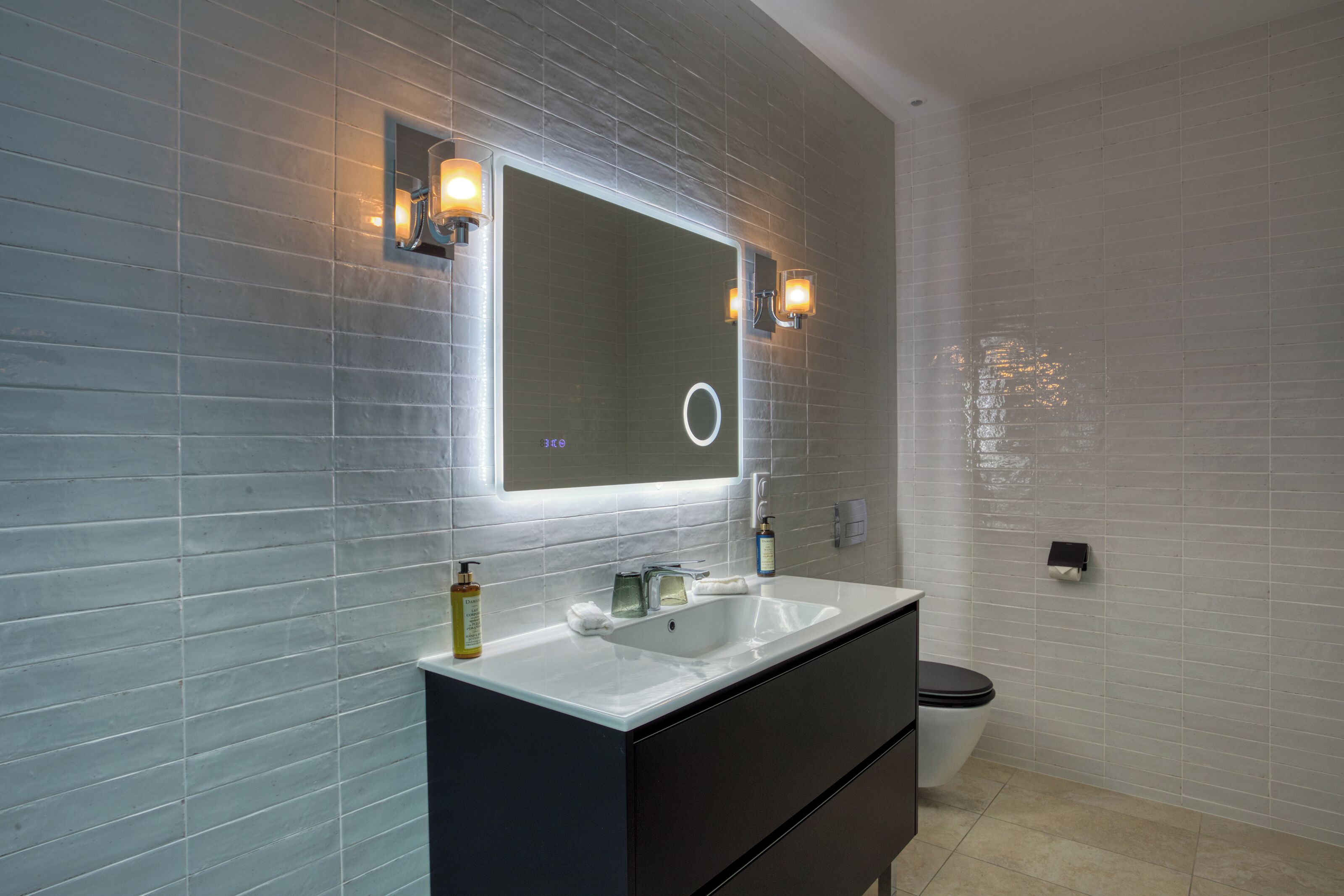 A bathroom with a large mirror, a white sink, and a black vanity.