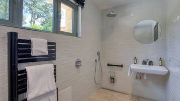Un baño moderno con ducha, lavamanos y toallero.