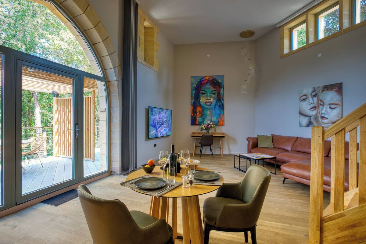 A modern dining area with a round table, two chairs, and a view of the outdoors.