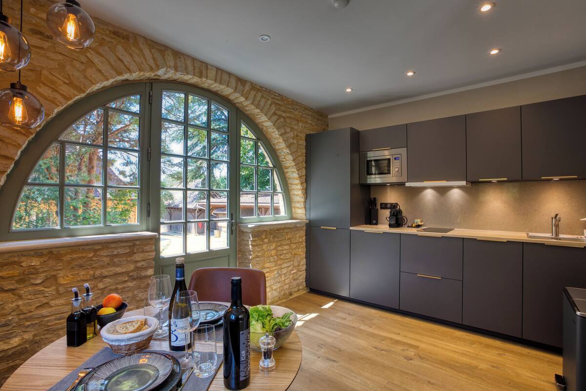 A modern kitchen with stone walls, large windows, and contemporary appliances.